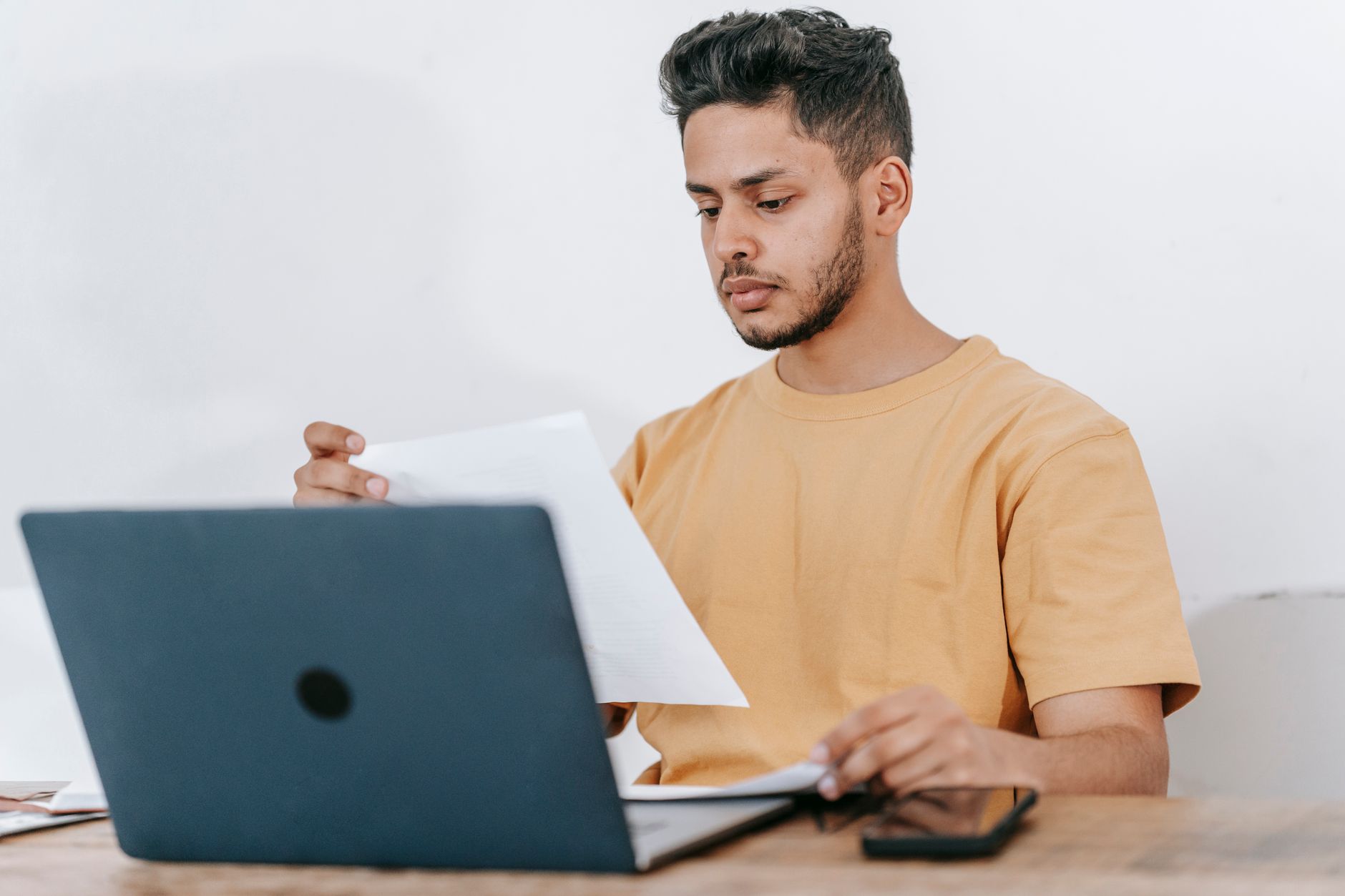 Freelancer reading a contract at a desk beside an open laptop